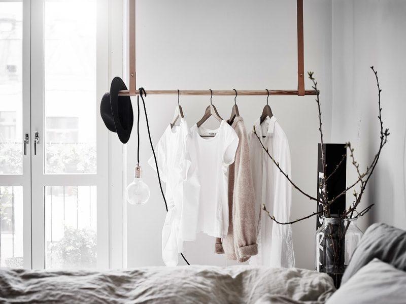 Maak eenvoudig je eigen kledingrek aan het plafond met een houten stang en leren straps.